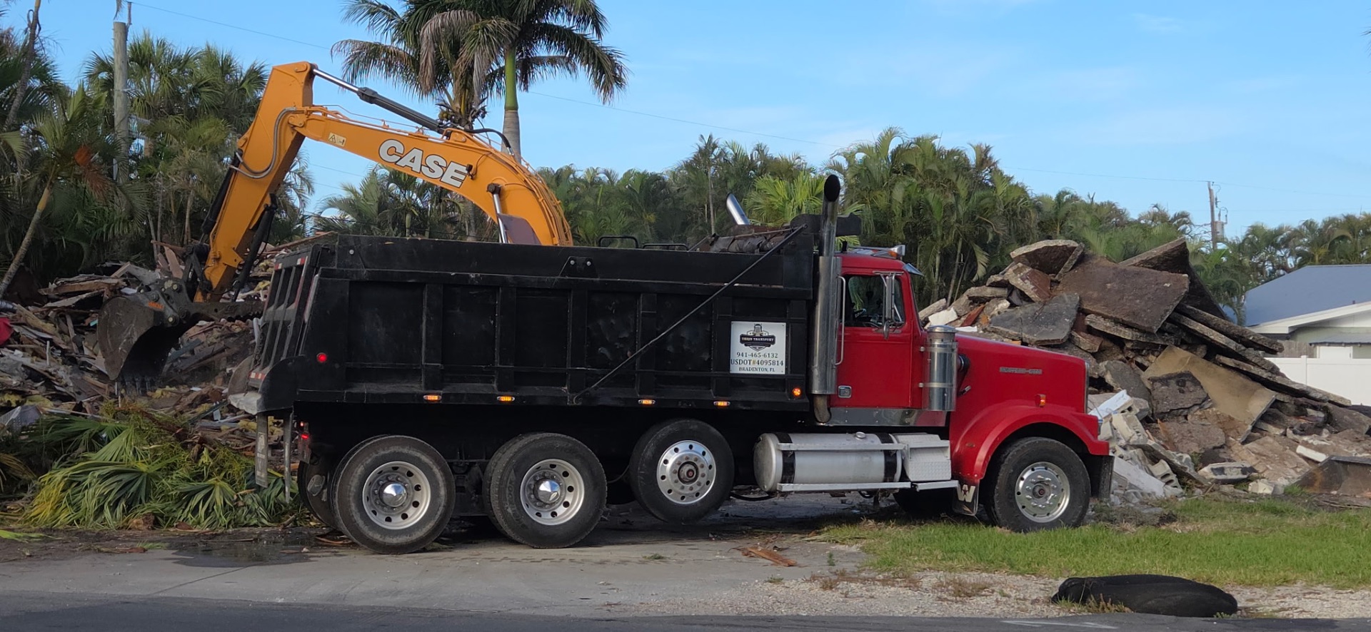 Excavator loading demolition debris into Trejo Transport dump truck in Bradenton